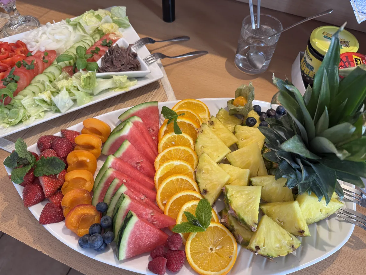 Obstplatte mit Ananas, Melone und Beeren zum Frühstück