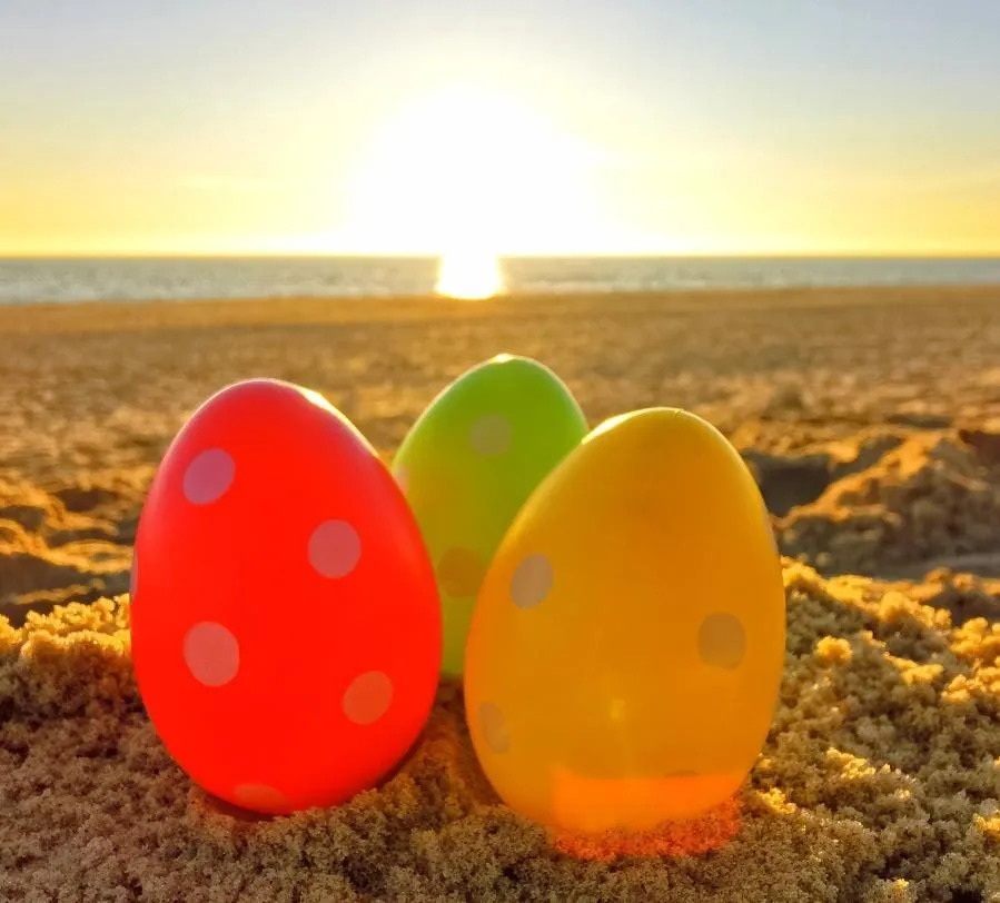 Colourful Easter eggs in the sand at sunset